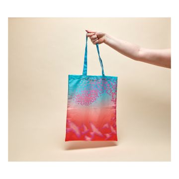 The sunset coloured Birds: Brilliant and Bizarre Tote Bag being held up by a model's hand against a beige background.
